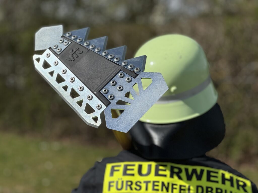 Foto von einem Feuerwehrmann, der das Vegetationsbrandwerkzeug Gorgui über der Schulter liegen hat.